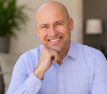 Robert Clark smiling warmly, chin resting on his hand, in his counseling office